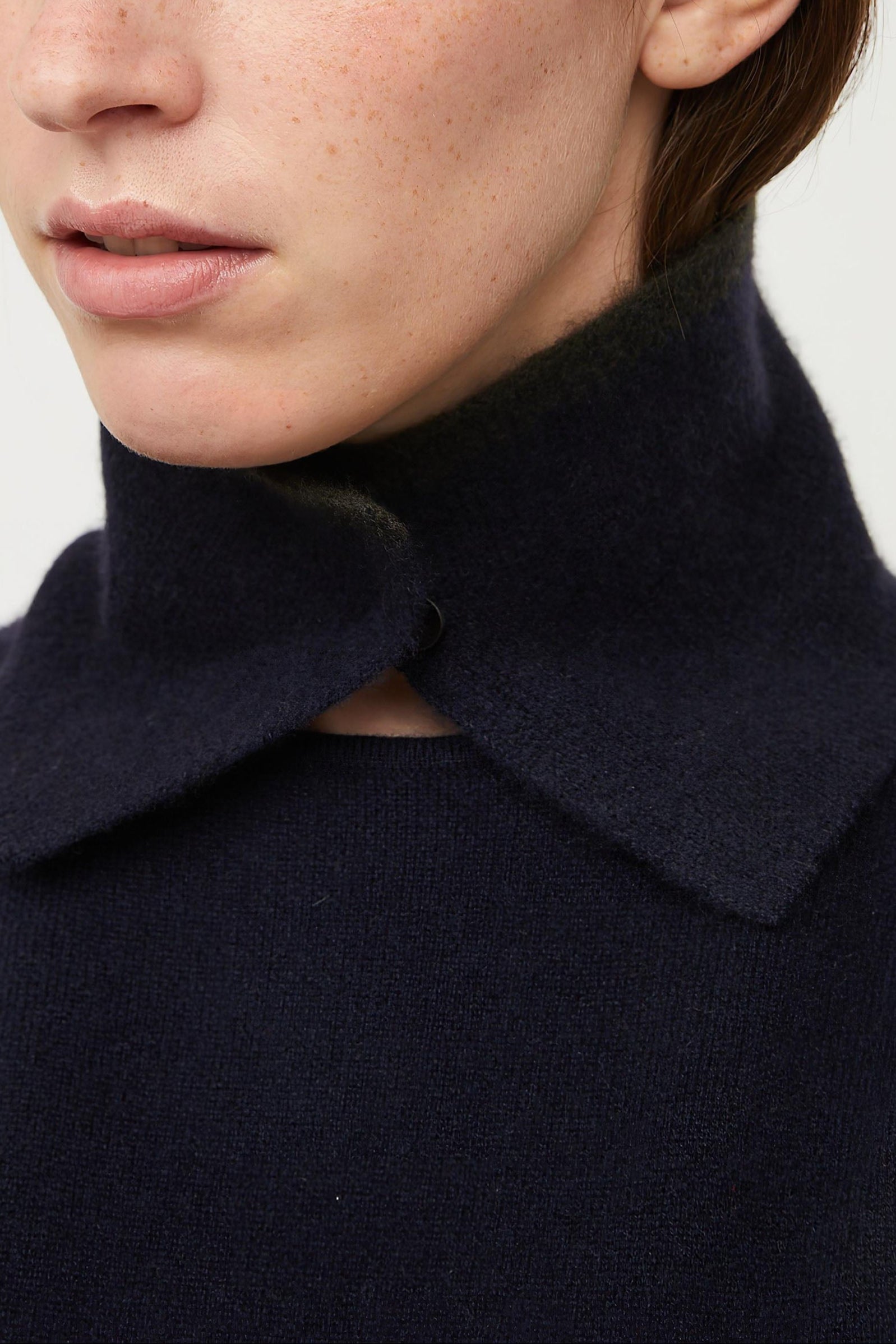 A person wearing an ocean-colored neck snood with a circle detail at the neckline.