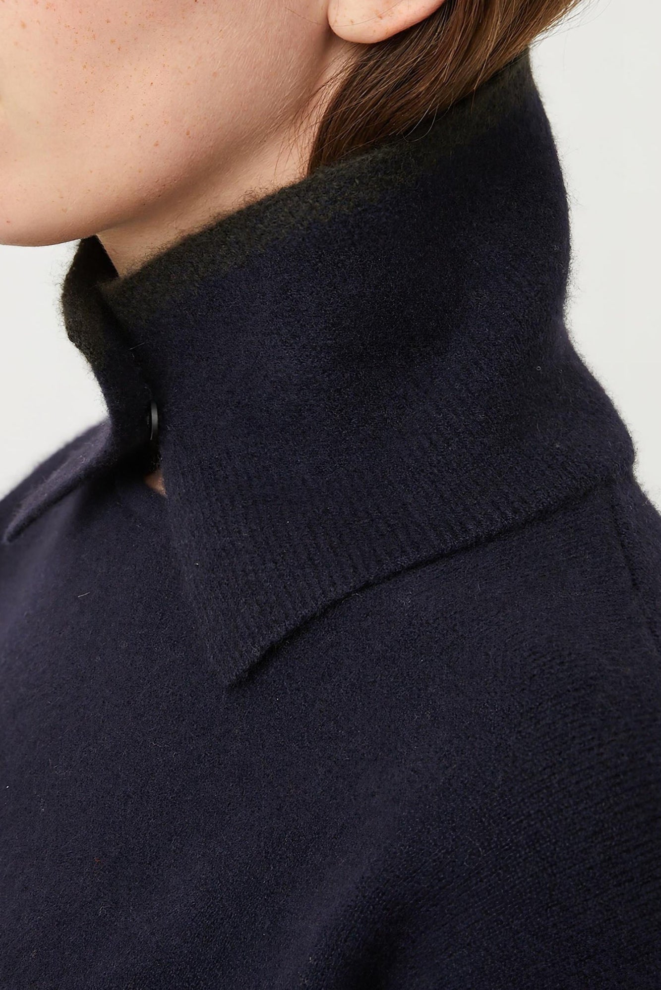 A person wearing an ocean-colored neck snood with a circle detail at the neckline.