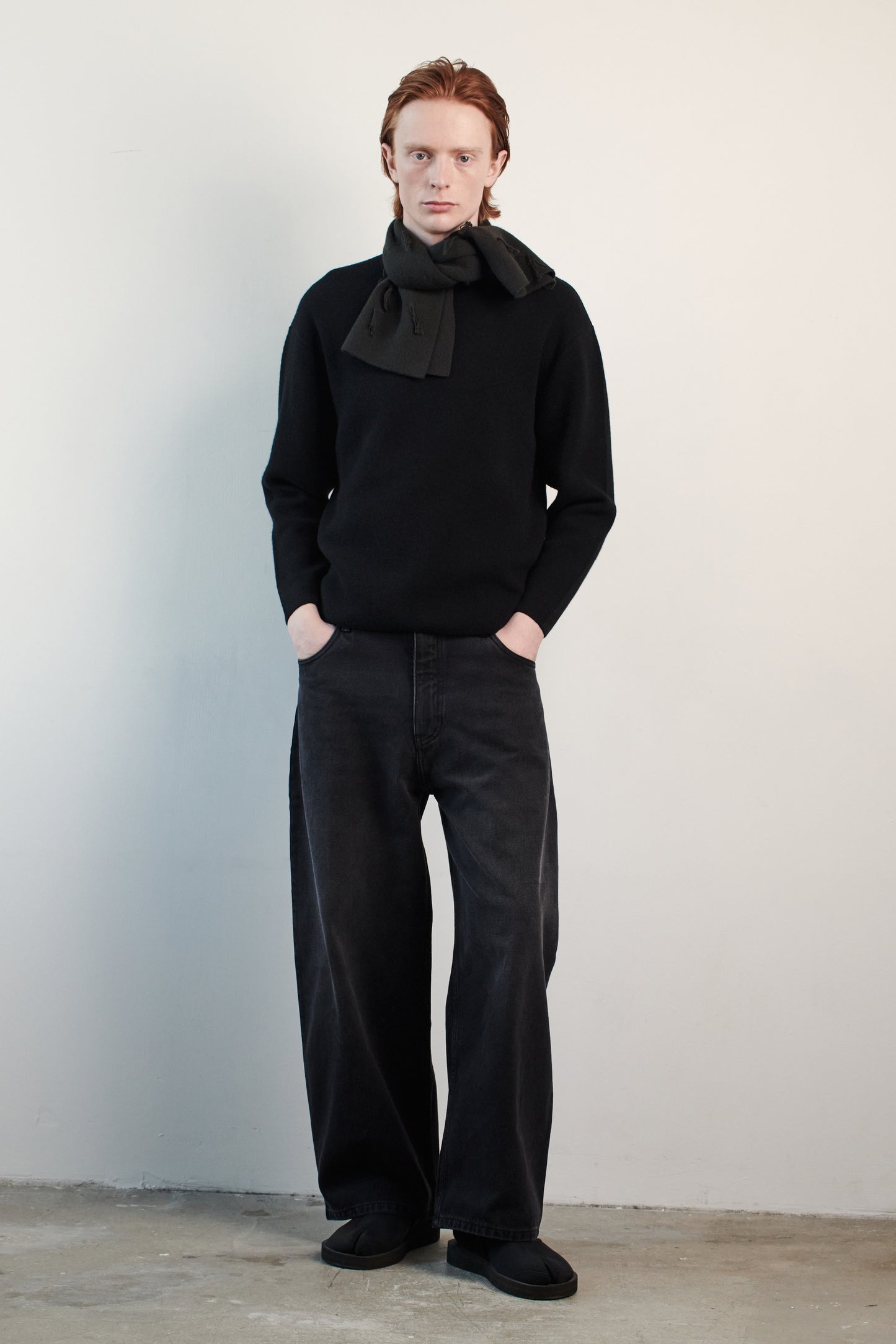This image features the Axa Sweater, highlighted in a minimalistic style with a black color. The sweater showcases an oversized fit with distinct drop shoulders and sculpted, rounded sleeves.