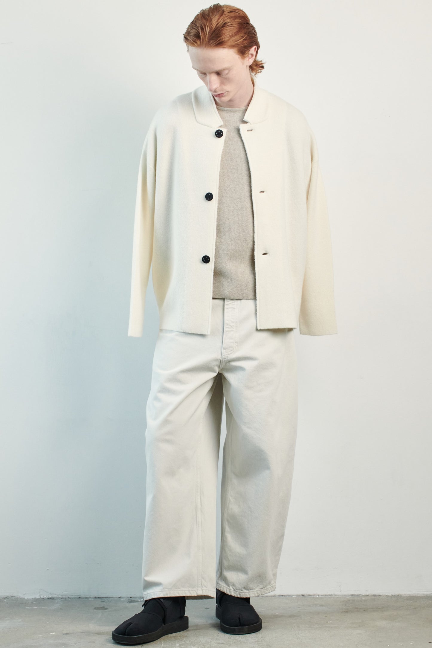 This image features a model wearing the Wind Jacket from Oyuna's core collection. The jacket is designed with a relaxed-fit and showcases a sophisticated look with its stand-up collar and welt pockets.