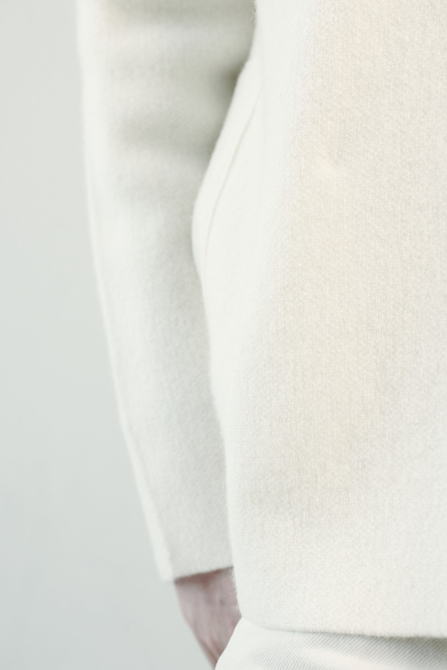 This image features a model wearing the Wind Jacket from Oyuna's core collection. The jacket is designed with a relaxed-fit and showcases a sophisticated look with its stand-up collar and welt pockets.