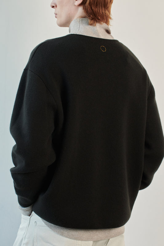 This image features the Axa Sweater, highlighted in a minimalistic style with a forest color. The sweater showcases an oversized fit with distinct drop shoulders and sculpted, rounded sleeves.