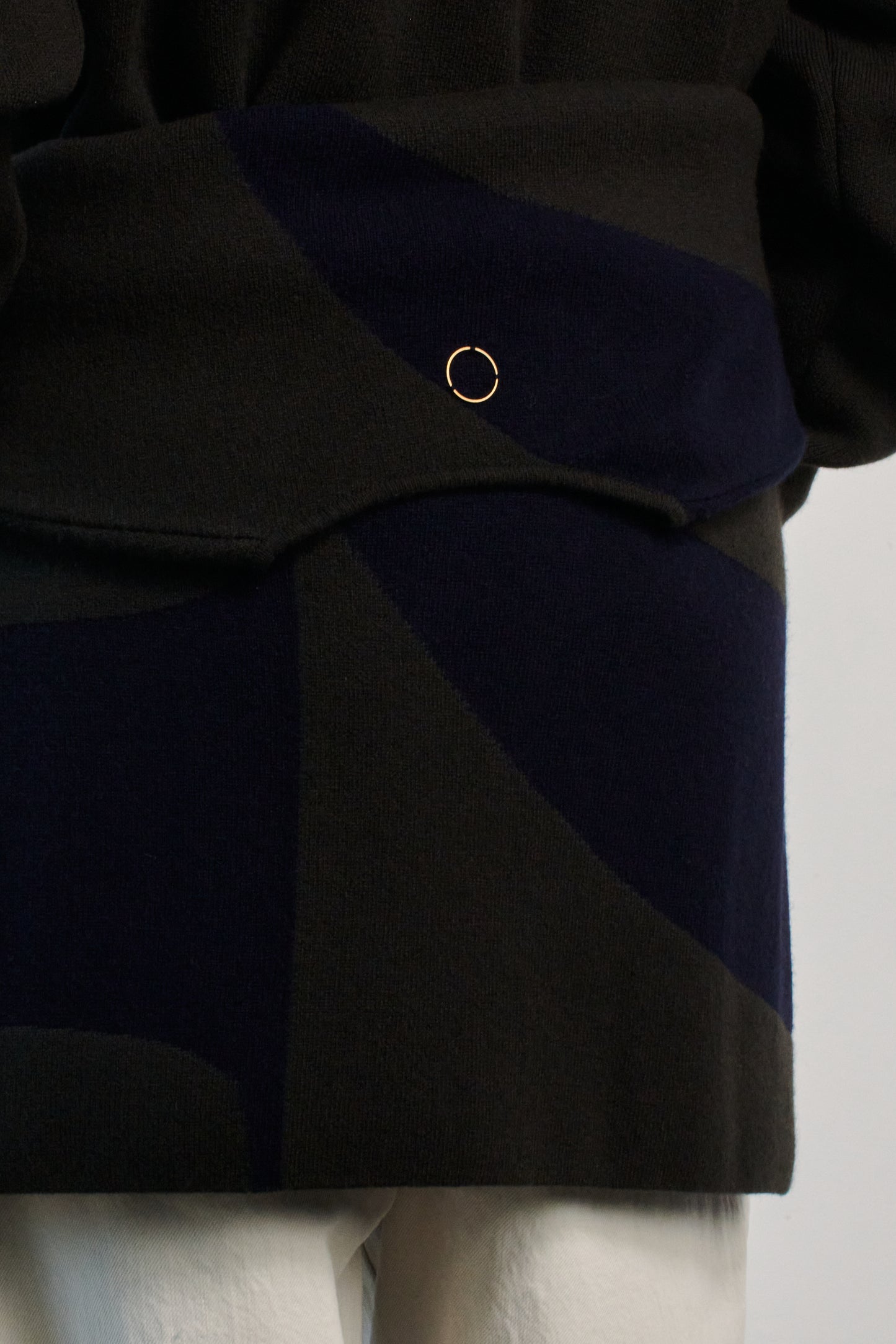 This image features the Arouc Sweater, a stylish and cozy garment that embodies a relaxed, everyday aesthetic. The sweater displays a boxy silhouette, crafted in a knitted jacquard print that forms an abstract, organic pattern in shades of green and navy blue.