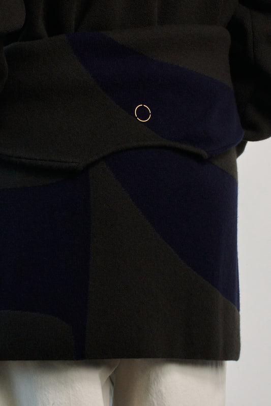 This image features the Arouc Sweater, a stylish and cozy garment that embodies a relaxed, everyday aesthetic. The sweater displays a boxy silhouette, crafted in a knitted jacquard print that forms an abstract, organic pattern in shades of green and navy blue.