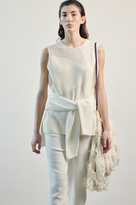 This image features the Duon Top, a stylish and comfortable cashmere knit vest in a subtle ivory color. The vest is designed with a boxy silhouette and fitted shoulders, creating a relaxed yet fitted look.