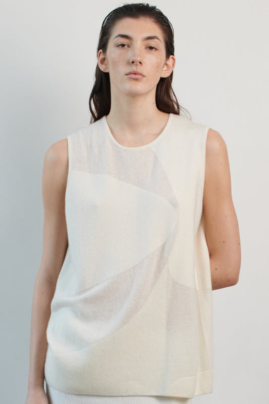 This image features the Duon Top, a stylish and comfortable cashmere knit vest in a subtle ivory color. The vest is designed with a boxy silhouette and fitted shoulders, creating a relaxed yet fitted look.