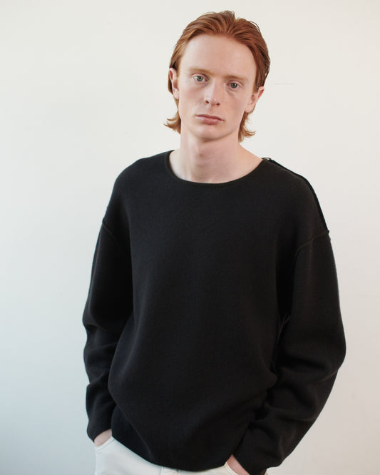 This image features the Axa Sweater, highlighted in a minimalistic style with a forest color. The sweater showcases an oversized fit with distinct drop shoulders and sculpted, rounded sleeves.