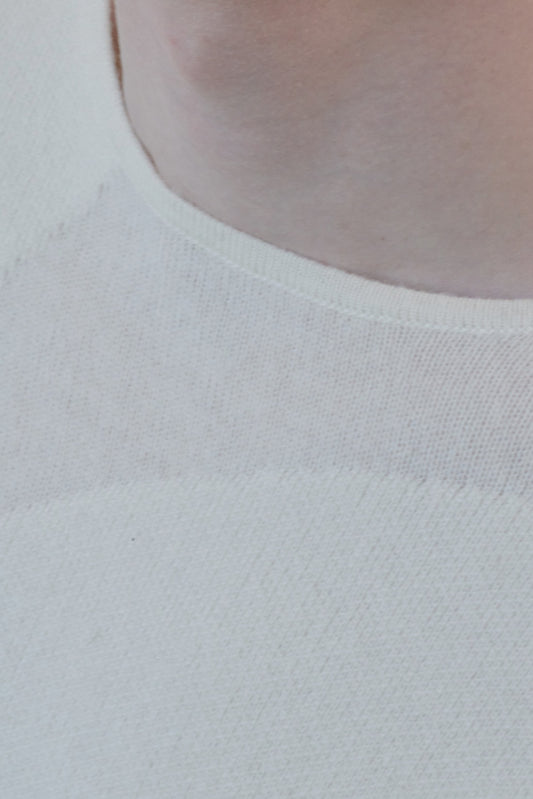 This image features the Arouc Sweater, a stylish and cozy garment that embodies a relaxed, everyday aesthetic. The sweater displays a boxy silhouette, crafted in a knitted jacquard print that forms an abstract, organic pattern in shades of ivory and feather.