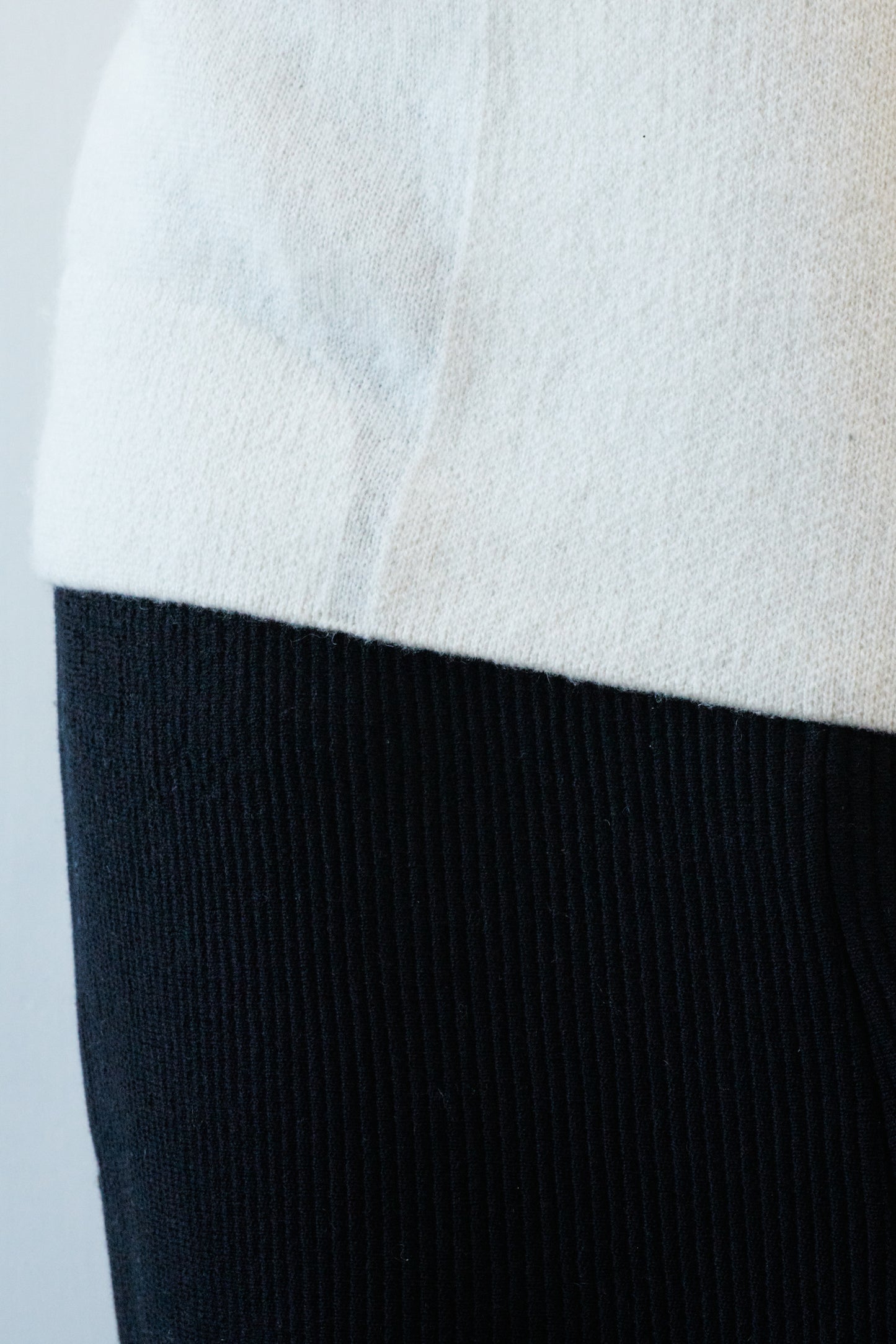 This image features the Arouc Sweater, a stylish and cozy garment that embodies a relaxed, everyday aesthetic. The sweater displays a boxy silhouette, crafted in a knitted jacquard print that forms an abstract, organic pattern in shades of ivory and feather.