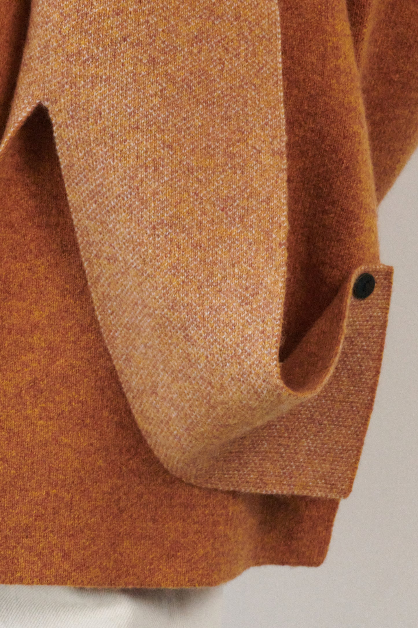 This image features the Ayal Jacket, a stylish sleeveless cashmere jacket displayed on a female model. The jacket is characterized by its asymmetric design, with a distinctive slit on the front left panel and button details on the front hem, adding a touch of uniqueness to its appearance.