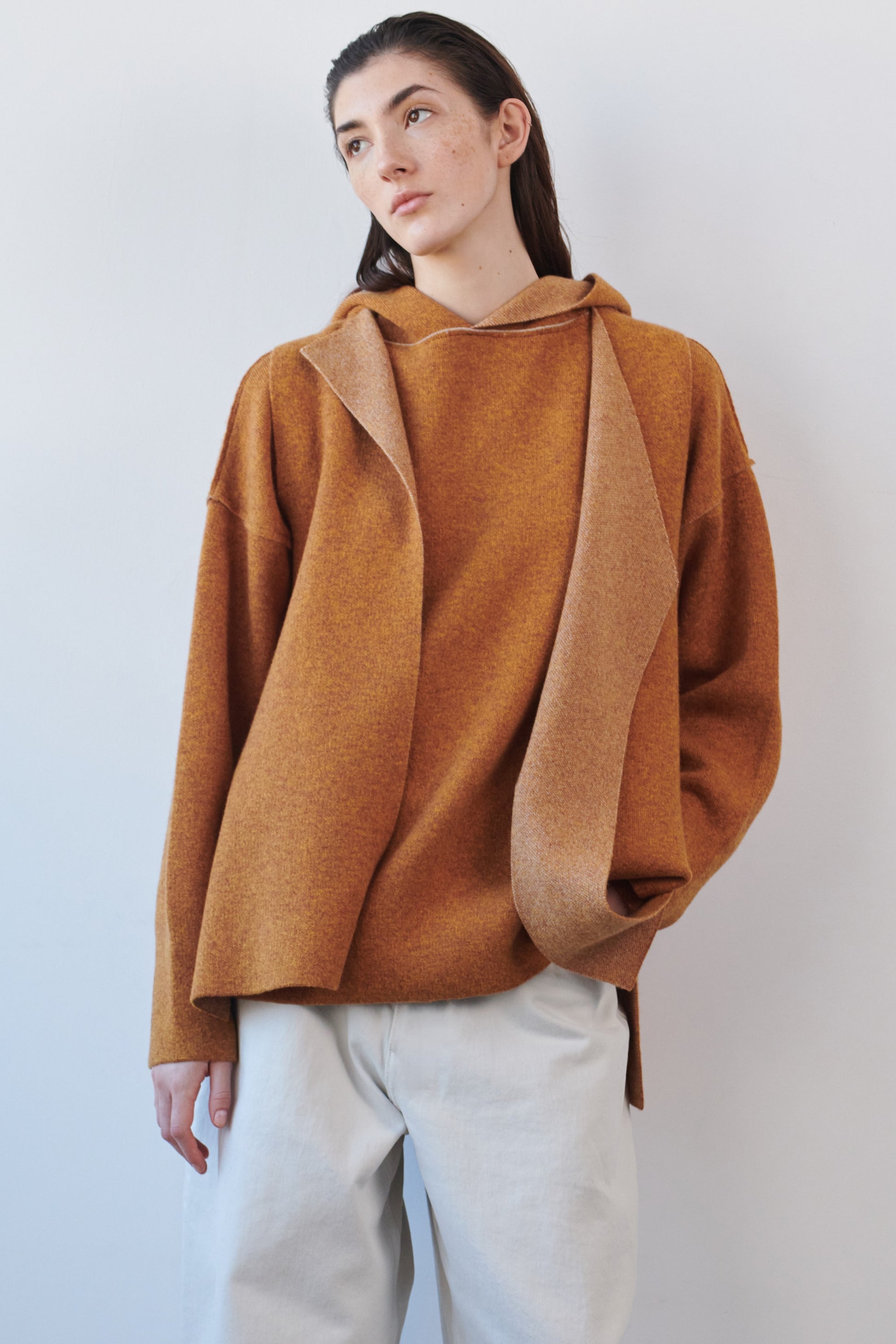 This image features the Ayal Jacket, a stylish sleeveless cashmere jacket displayed on a female model. The jacket is characterized by its asymmetric design, with a distinctive slit on the front left panel and button details on the front hem, adding a touch of uniqueness to its appearance.