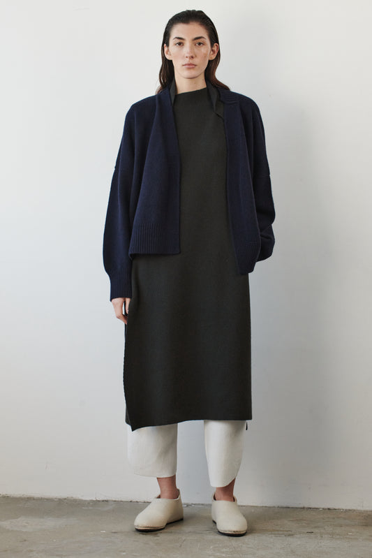 This image features the Aire Cardigan, a luxurious, chunky open cardigan made from pure cashmere. The cardigan is displayed on a model, showcasing its sleek ocean color and stylish design elements.