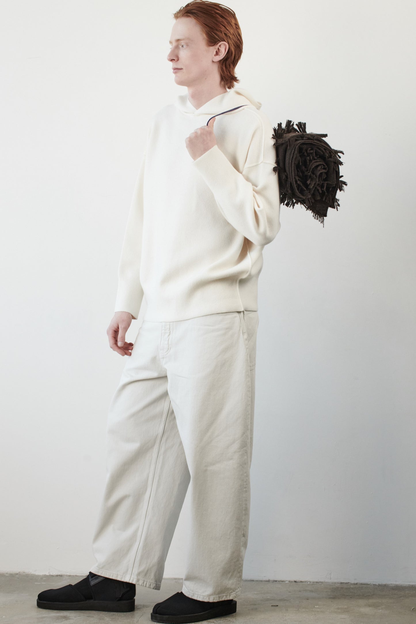 This image features a luxurious ivory cashmere hoodie, displayed against a neutral background to emphasize its design and color. The hoodie boasts a modern and minimalist look, with a soft and snug fit that promises comfort and style. Draped over the shoulder is a chocolate travel throw