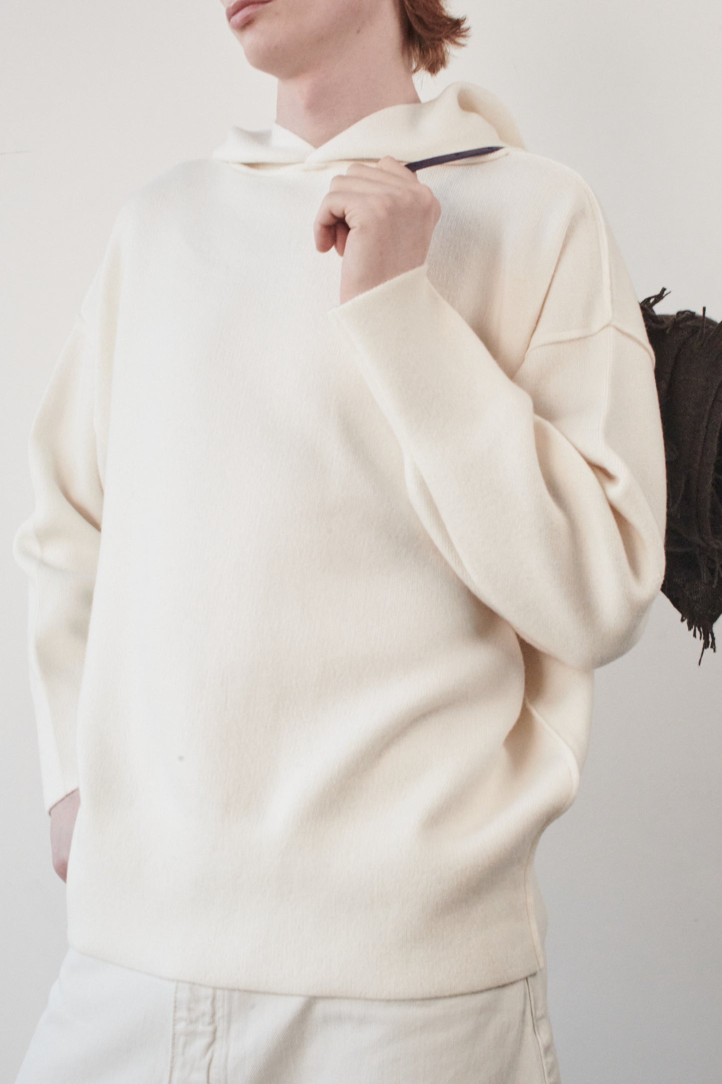 This image features a luxurious ivory cashmere hoodie, displayed against a neutral background to emphasize its design and color. The hoodie boasts a modern and minimalist look, with a soft and snug fit that promises comfort and style. Draped over the shoulder is a chocolate travel throw
