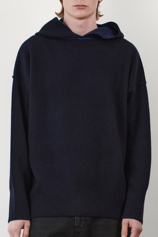 A closeup featuring a stylish and modern Seku Hoodie, presented in a quiet, modern ocean color. The model is seen wearing the hoodie, which drapes comfortably over the body, highlighting its soft and luxurious feel.