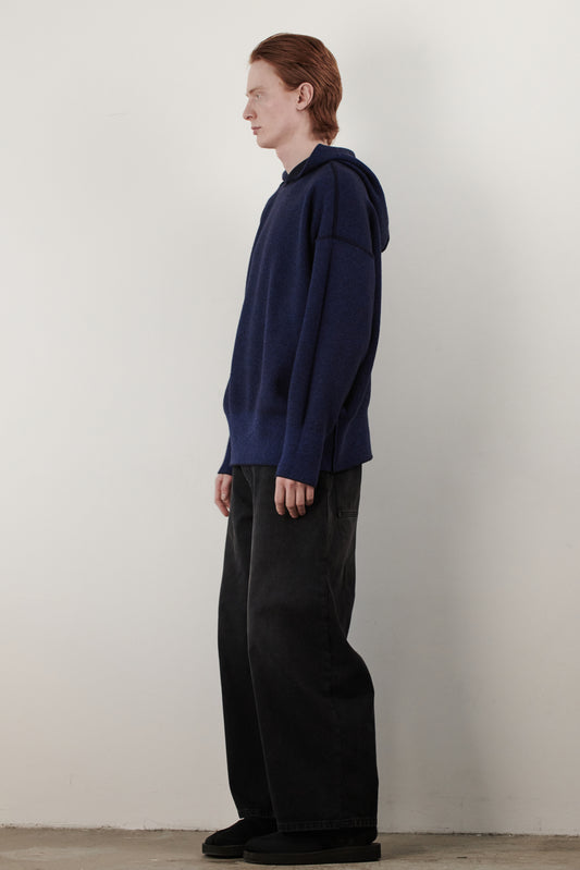 This side view image features a stylish and modern Seku Hoodie, presented in a quiet, modern ocean color. The model is seen wearing the hoodie, which drapes comfortably over the body, highlighting its soft and luxurious feel.