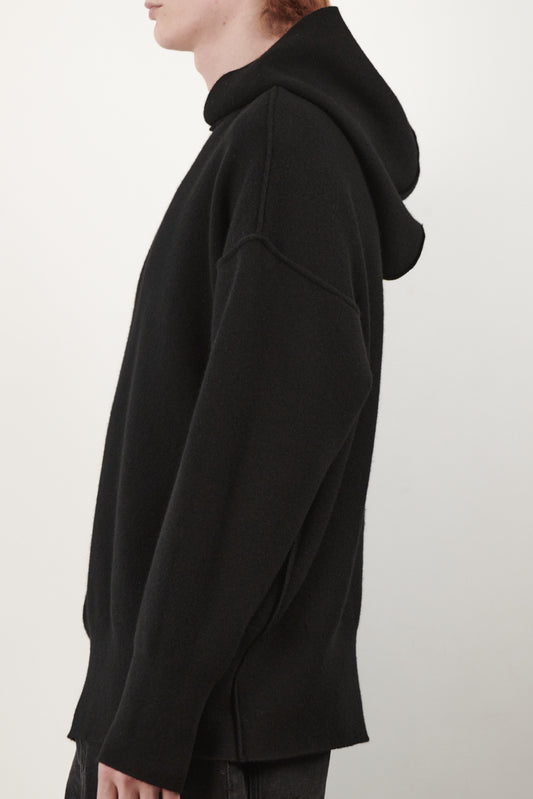 This side view image features a luxurious black cashmere hoodie, displayed against a neutral background to emphasize its design and color. The hoodie boasts a modern and minimalist look, with a soft and snug fit that promises comfort and style.