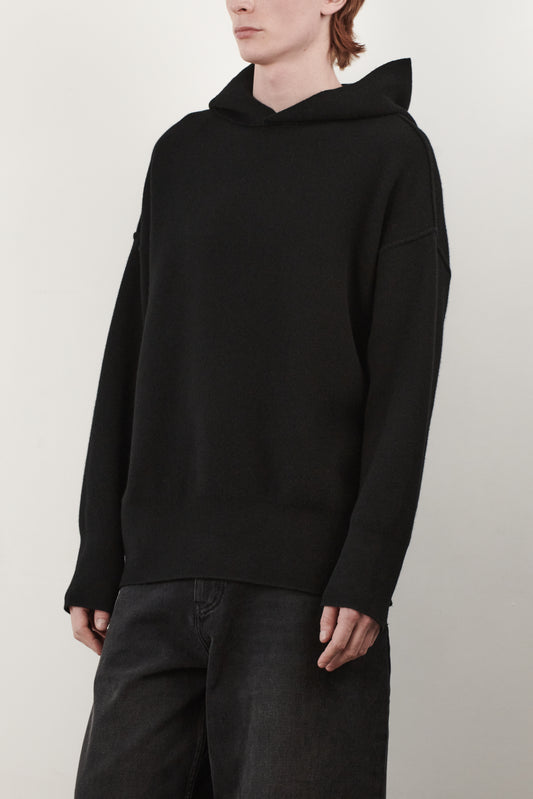 This side view image features a luxurious black cashmere hoodie, displayed against a neutral background to emphasize its design and color. The hoodie boasts a modern and minimalist look, with a soft and snug fit that promises comfort and style.
