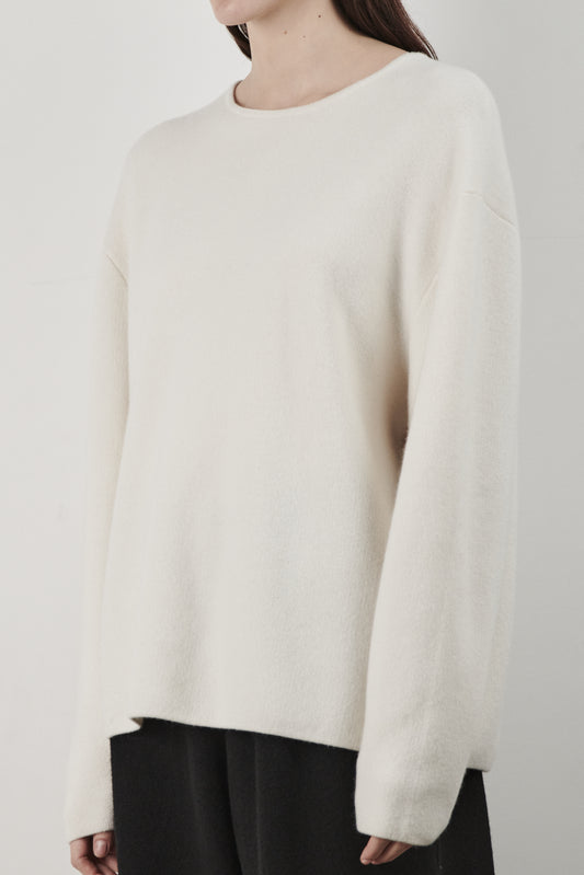 This image features the Axa Sweater, a stylish and comfortable piece that showcases an oversized fit with drop shoulders and sculpted, rounded sleeves. The sweater is knitted using a structured jacquard stitch, which adds texture and depth to its appearance.