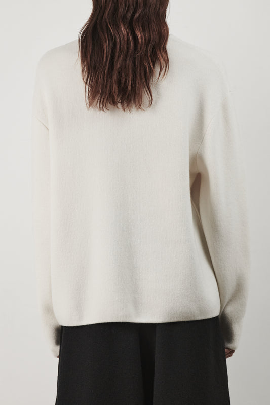 This image features the Axa Sweater, a stylish and comfortable piece that showcases an oversized fit with drop shoulders and sculpted, rounded sleeves. The sweater is knitted using a structured jacquard stitch, which adds texture and depth to its appearance.