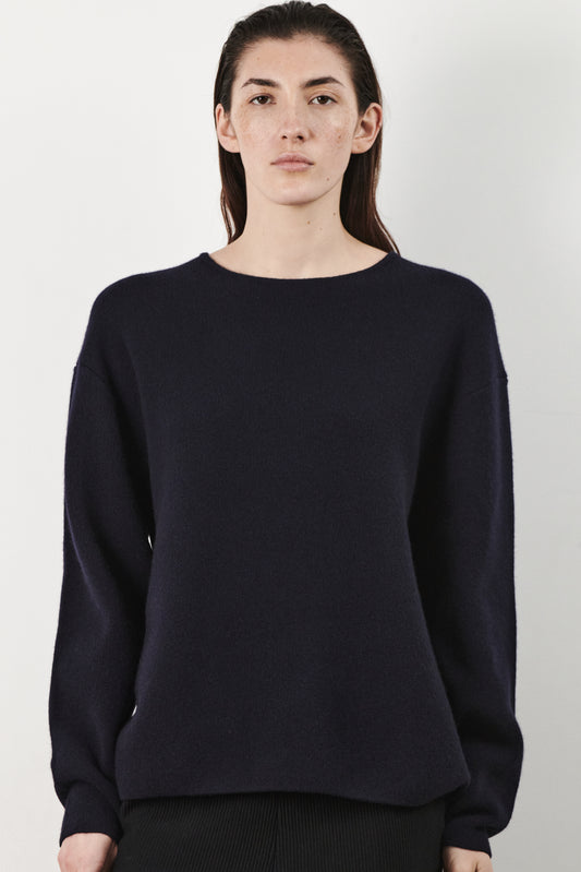 This image features the Axa Sweater, a stylish and comfortable piece that showcases an oversized fit with drop shoulders and sculpted, rounded sleeves. The sweater is knitted using a structured jacquard stitch, which adds texture and depth to its appearance.