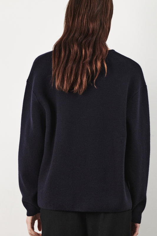 This image features the Axa Sweater, a stylish and comfortable piece that showcases an oversized fit with drop shoulders and sculpted, rounded sleeves. The sweater is knitted using a structured jacquard stitch, which adds texture and depth to its appearance.