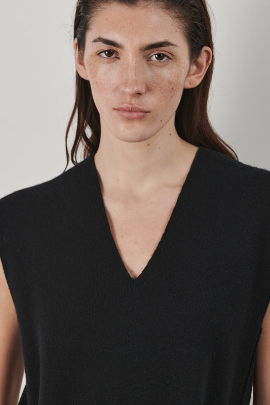 This image features the Mauni Dress, a stylish sleeveless V-neck dress crafted in a jacquard knit. The dress displays an elegant and modern silhouette, highlighted by its intricate texture and a sleek, contrasting belt that enhances the waistline.