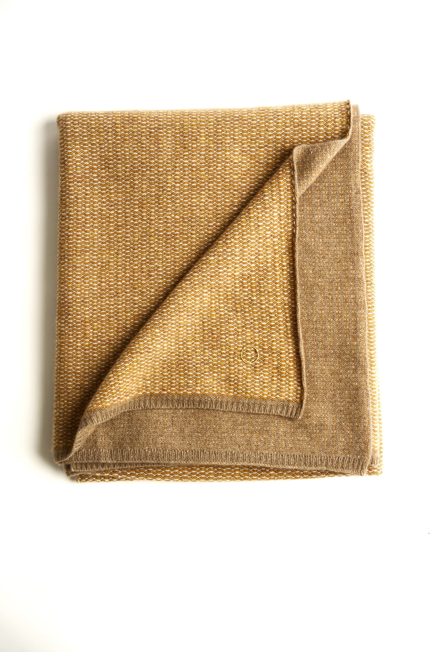 A flat lay image of the Quadro throw in honey & taupe, with a subtle circle detail in the corner