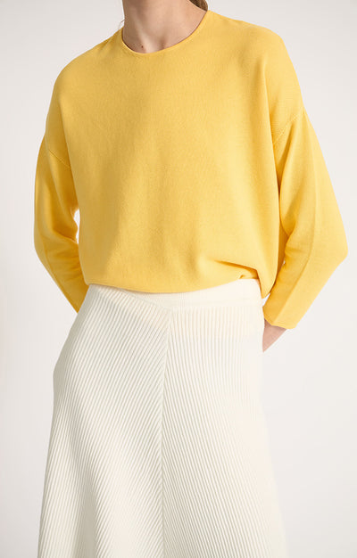 Woman wearing Sabi cotton sweater with dropped shoulders and cropped sleeves in colour Lemon.