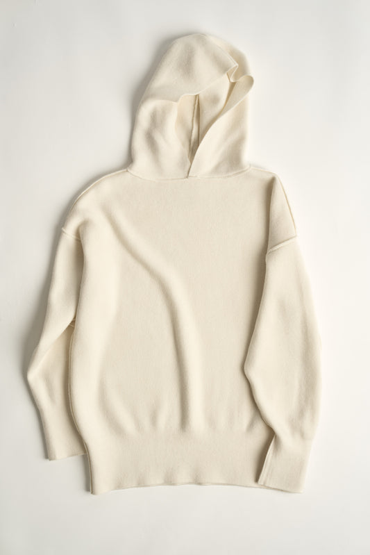 This image features a luxurious ivory cashmere hoodie, displayed against a neutral background to emphasize its design and color. The hoodie boasts a modern and minimalist look, with a soft and snug fit that promises comfort and style.