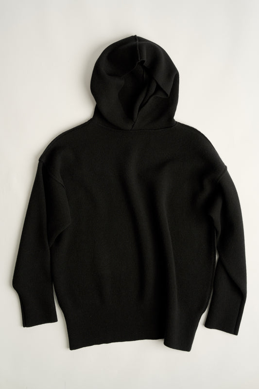 This image features a luxurious black cashmere hoodie, displayed against a neutral background to emphasize its design and color. The hoodie boasts a modern and minimalist look, with a soft and snug fit that promises comfort and style.