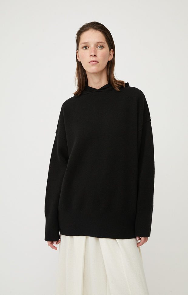 Woman wearing Seku knitted oversized cashmere hoodie in colour Black. 