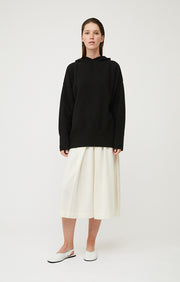 Woman wearing Seku knitted oversized cashmere hoodie in colour Black. 