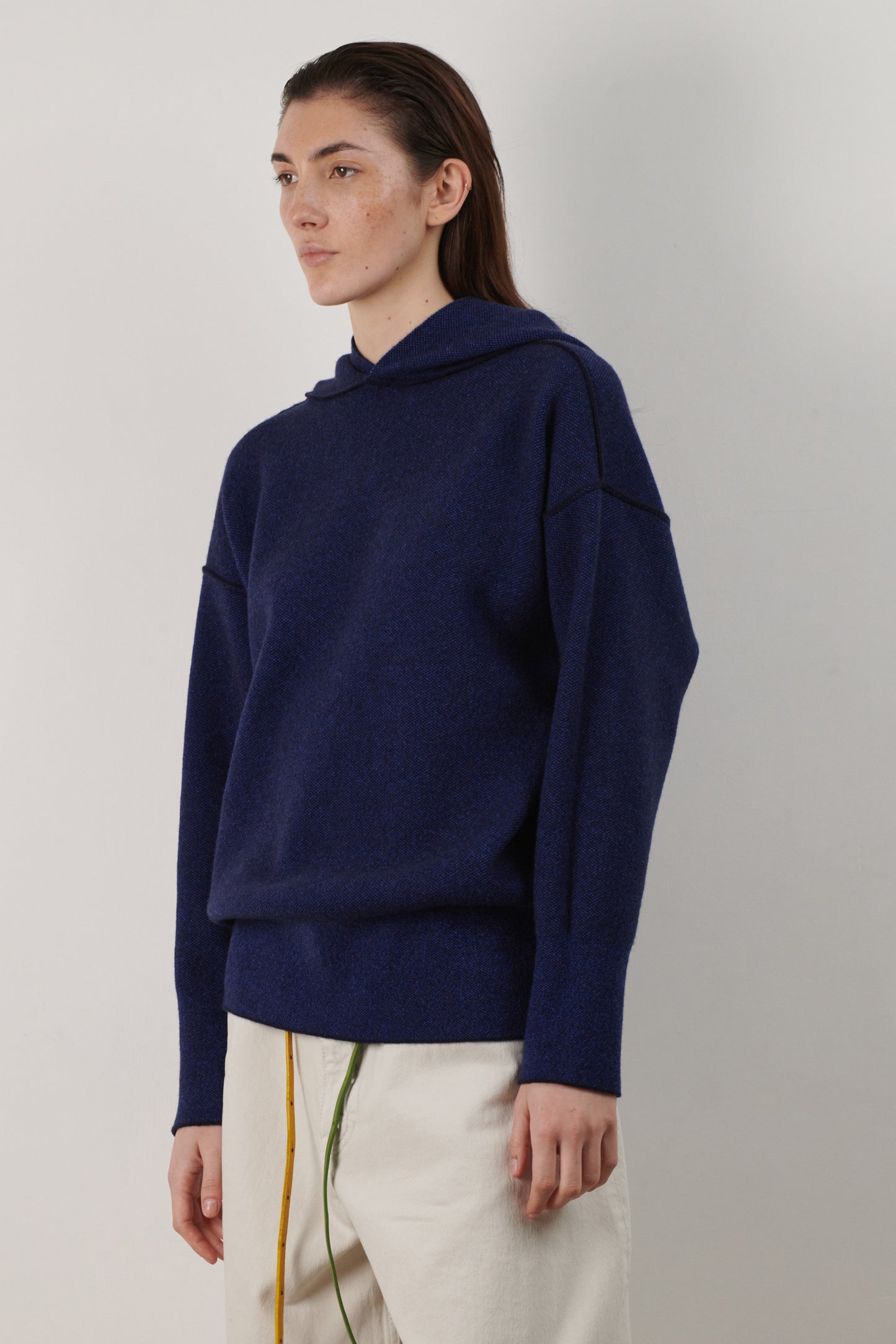 This image features a luxurious ocean & wave cashmere hoodie, modeled by a female. The hoodie boasts a modern and minimalist design, with a relaxed fit that enhances its appeal.