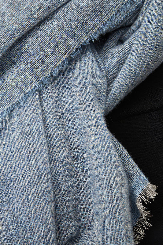This image displays the Sera Shawl, a luxurious and elegant accessory crafted from the finest cashmere. The shawl features a subtle two-tone effect, achieved through a combination of different colors on the warp and weft, which enhances its sophisticated appeal.