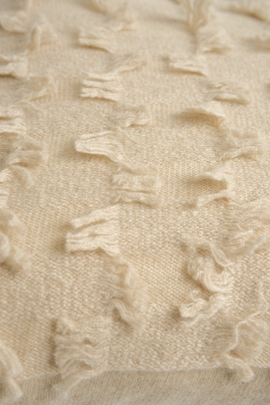 This image displays the Seren Cushion Cover, designed to bring a touch of serene elegance to any interior setting. The cushion cover features a distinct hand-cut fringe detail that adds a textured and dynamic touch.