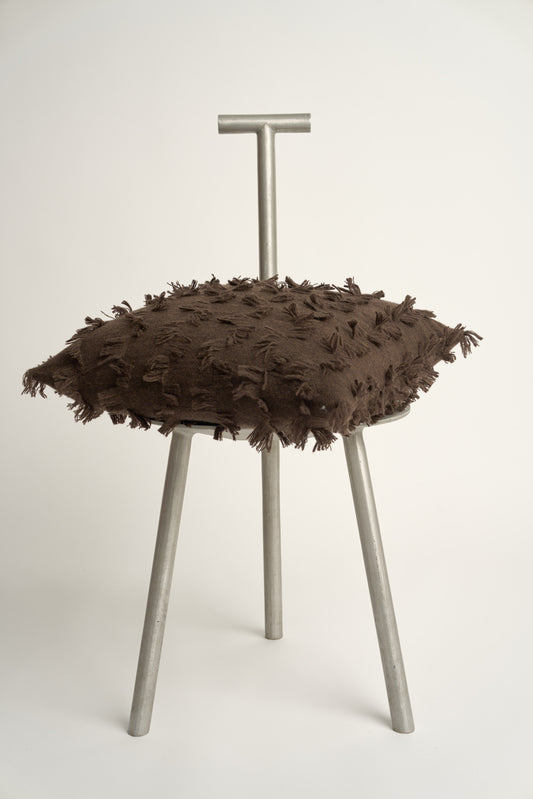 This image displays the Seren Cushion Cover, designed to bring a touch of serene elegance to any interior setting. The cushion cover features a distinct hand-cut fringe detail that adds a textured and dynamic touch.