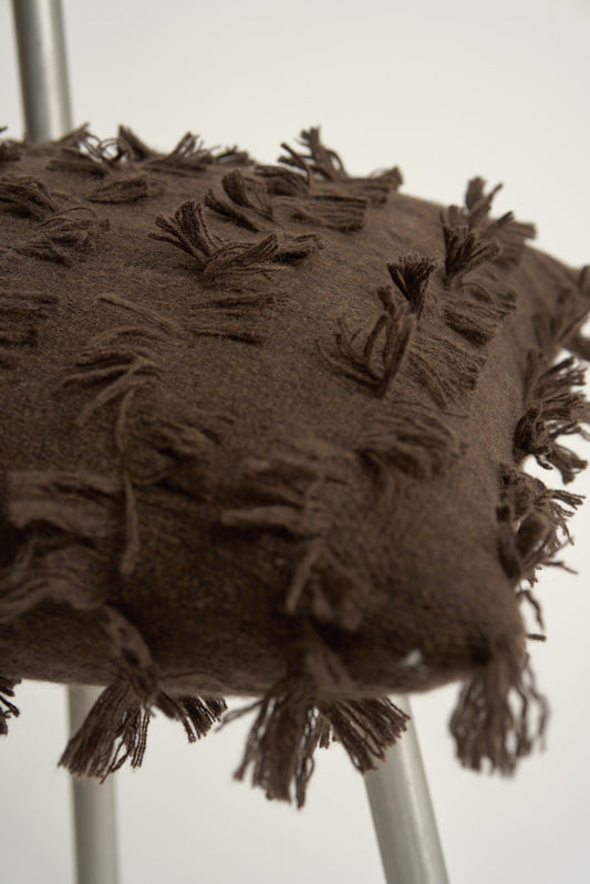 This image displays the Seren Cushion Cover, designed to bring a touch of serene elegance to any interior setting. The cushion cover features a distinct hand-cut fringe detail that adds a textured and dynamic touch.