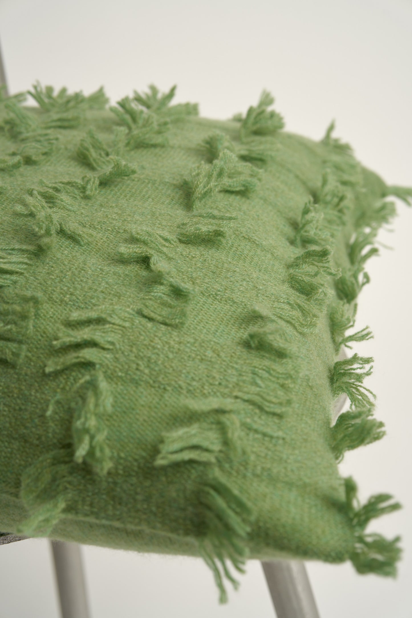 This image displays the Seren Cushion Cover, designed to bring a touch of serene elegance to any interior setting. The cushion cover features a distinct hand-cut fringe detail that adds a textured and dynamic touch.