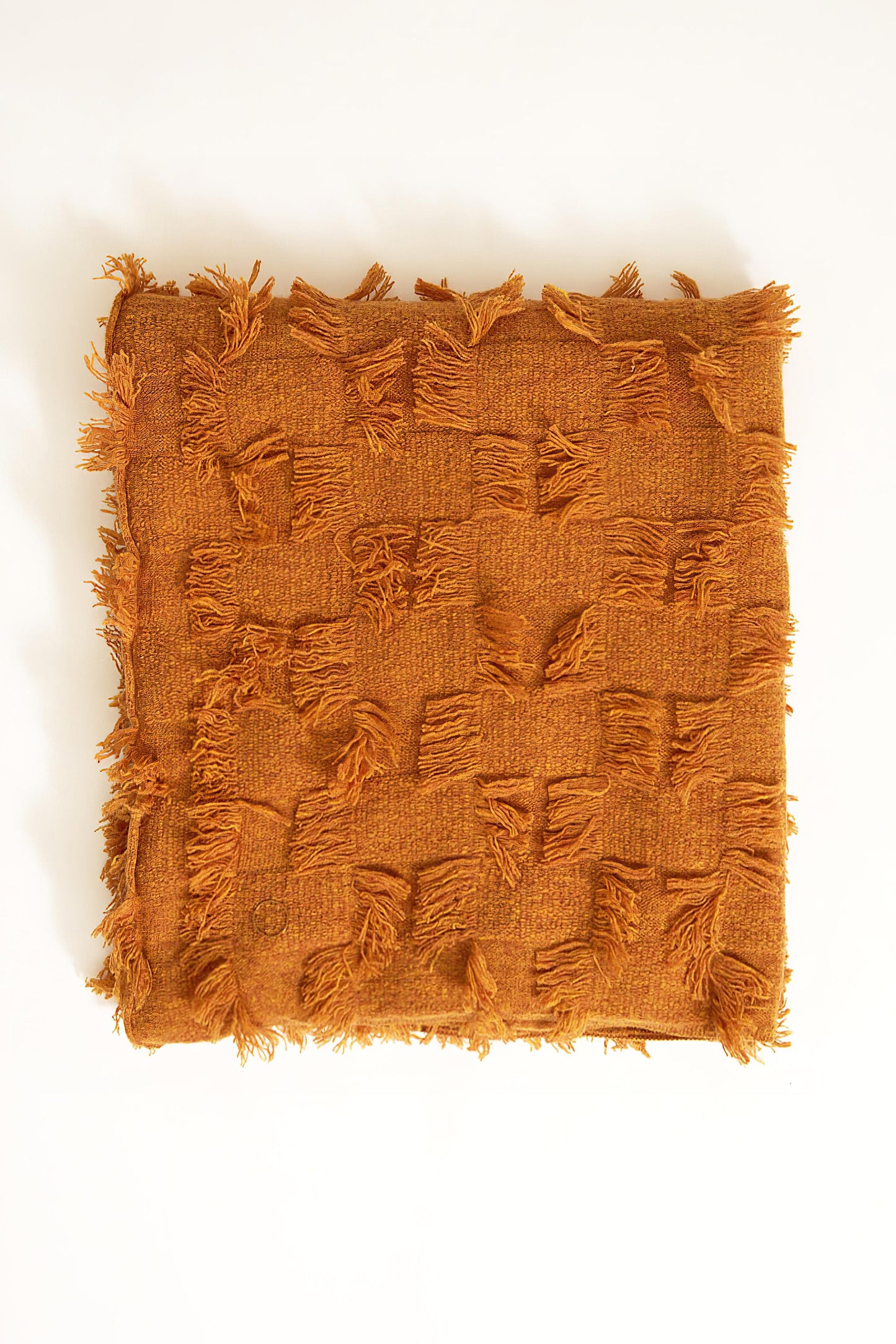 This image displays the Seren Throw, a luxurious cashmere knitted throw featuring a distinctive hand-cut fringe detail. The throw is presented in a bright, warm honey color, enhancing its elegant and sophisticated appearance.