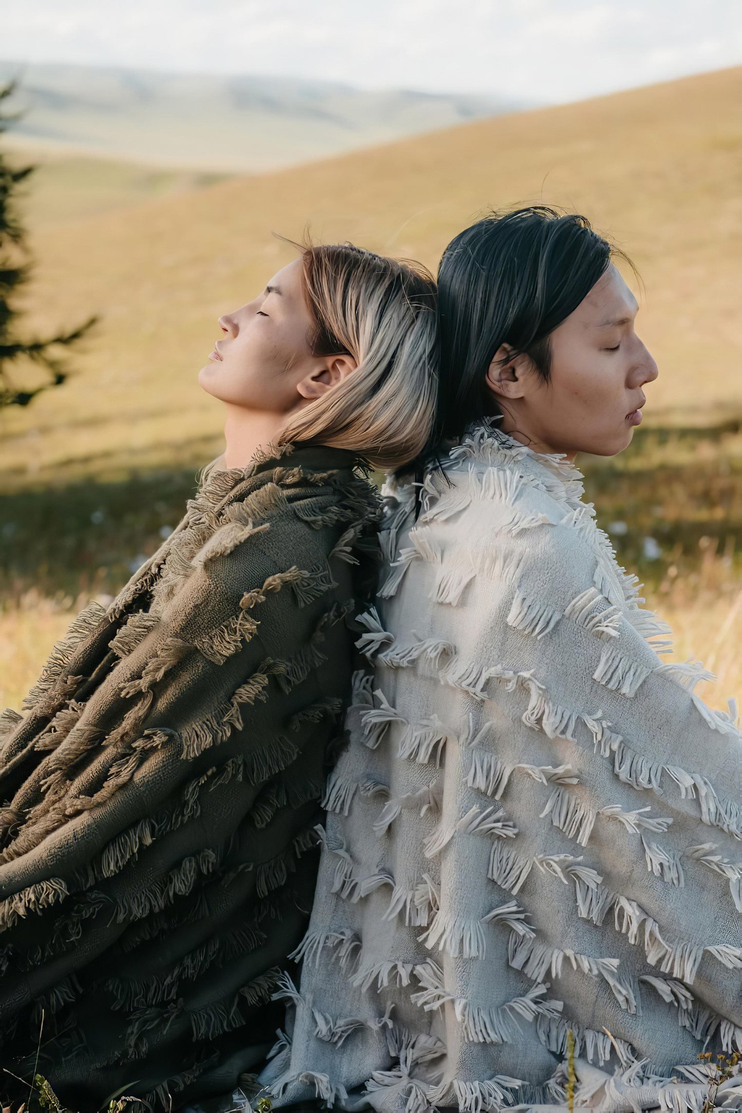This image features two individuals enjoying the serene outdoors, each draped in a cozy, luxurious cashmere throw. The throws are adorned with a distinctive hand-cut fringe detail that adds a three-dimensional texture, enhancing the aesthetic appeal of any space.