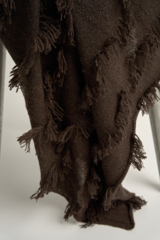 This image displays the Seren Throw, a luxurious cashmere knitted throw featuring a distinctive hand-cut fringe detail. The throw is presented in a deep, rich brown color, enhancing its elegant and sophisticated appearance.