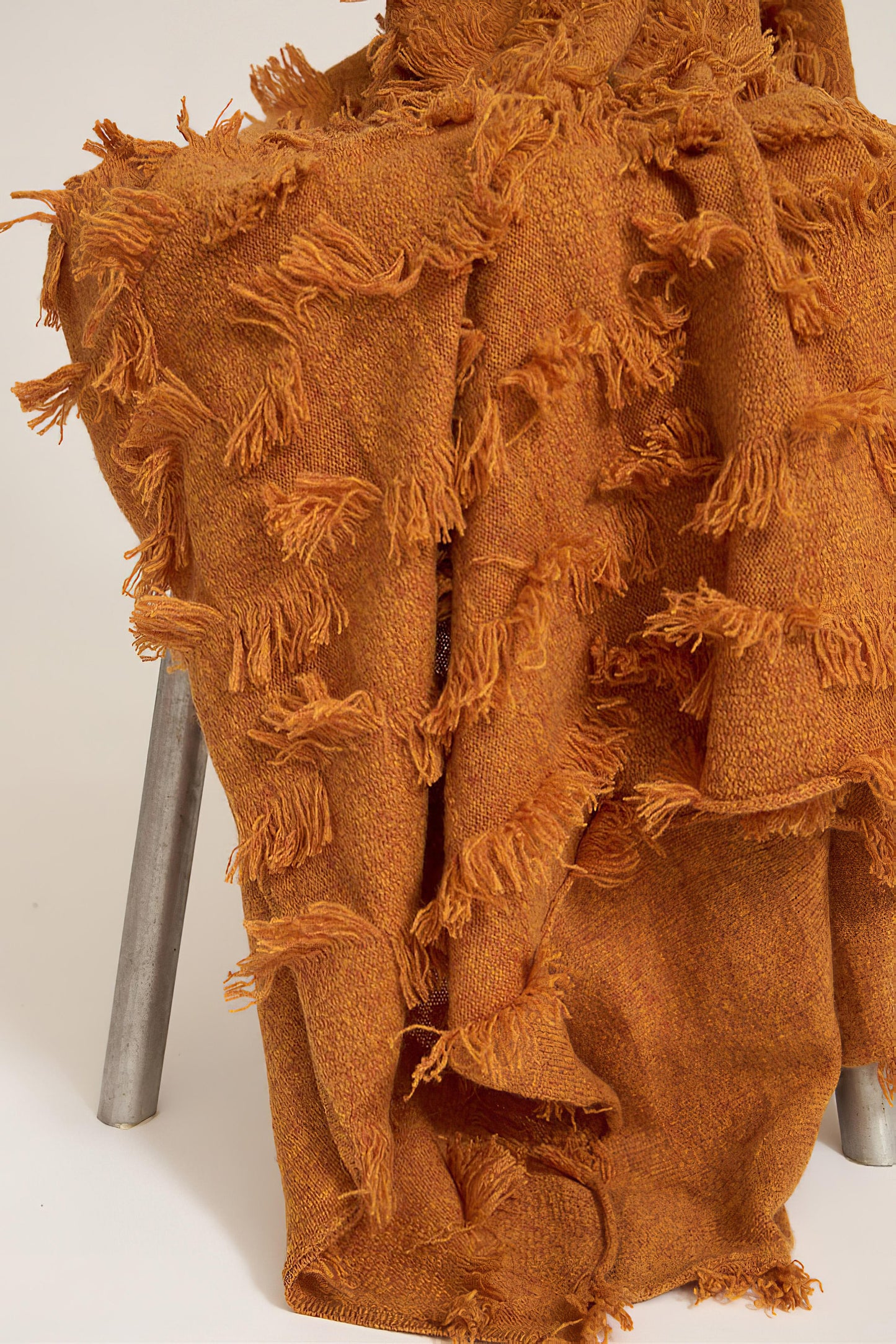A honey bedspread with hand-cut fringe detail, draped over a chair.