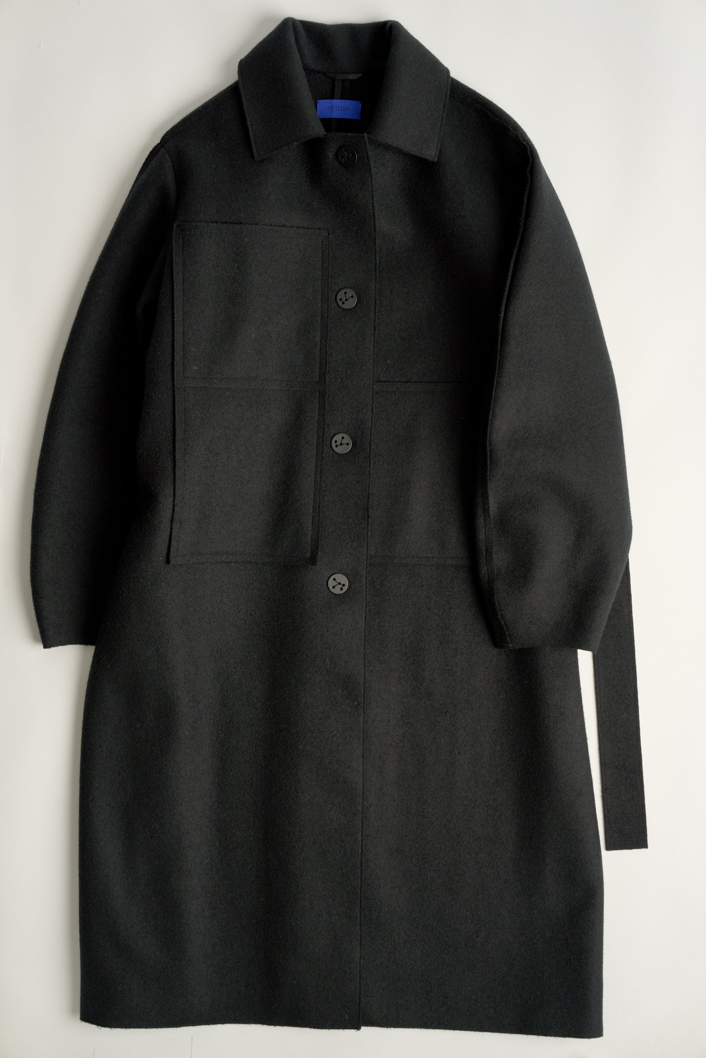 This image features a model wearing a sophisticated, heavyweight cashmere coat, which we refer to as the "Shield Coat". The coat is displayed in a deep, black color, enhancing its elegant and modern appeal.