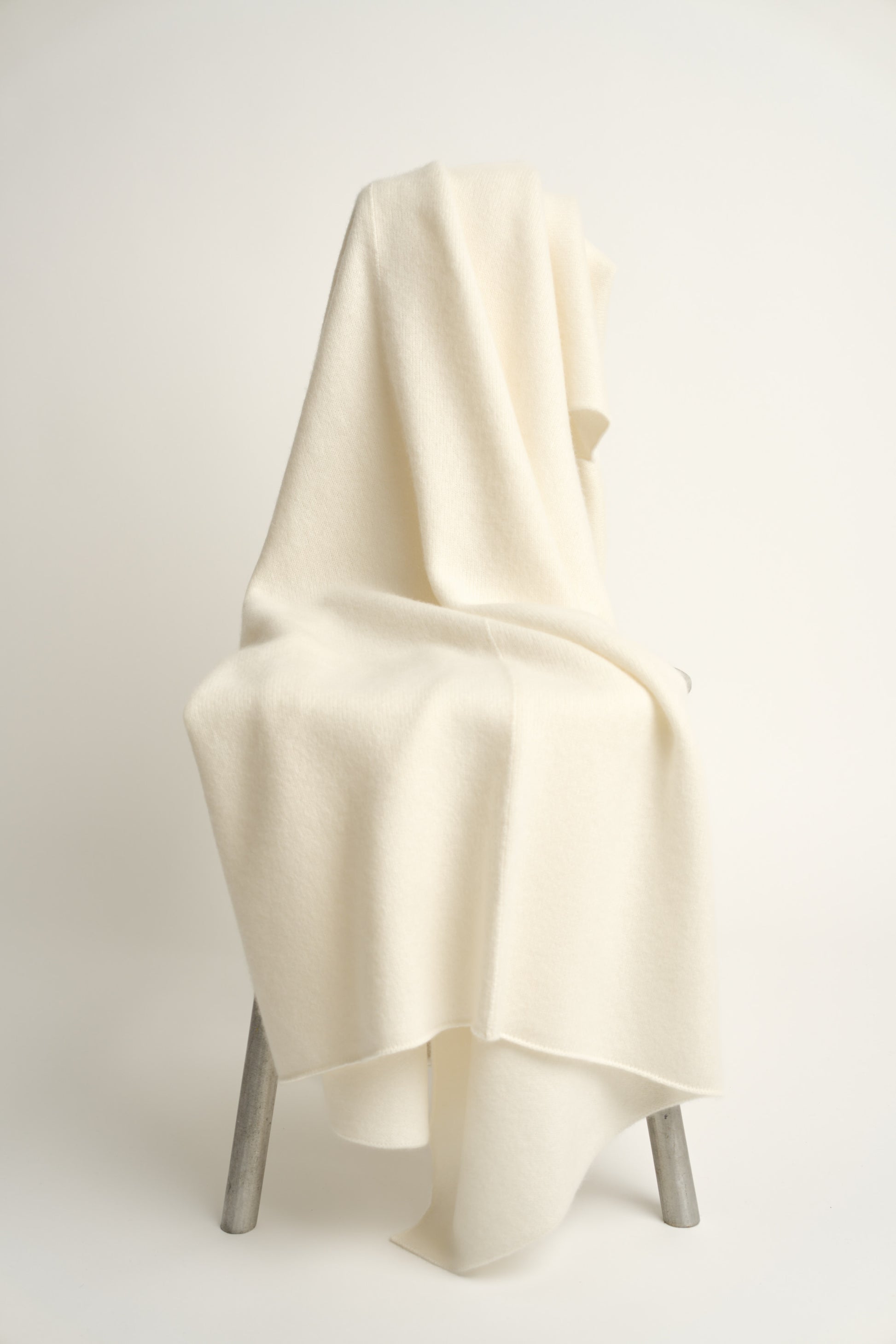 This image displays the Silence Throw, a knitted felted blanket that provides both warmth and a soft texture. Its gentle beige color contributes to its subtle and elegant design, making it a beautiful addition to any living space.