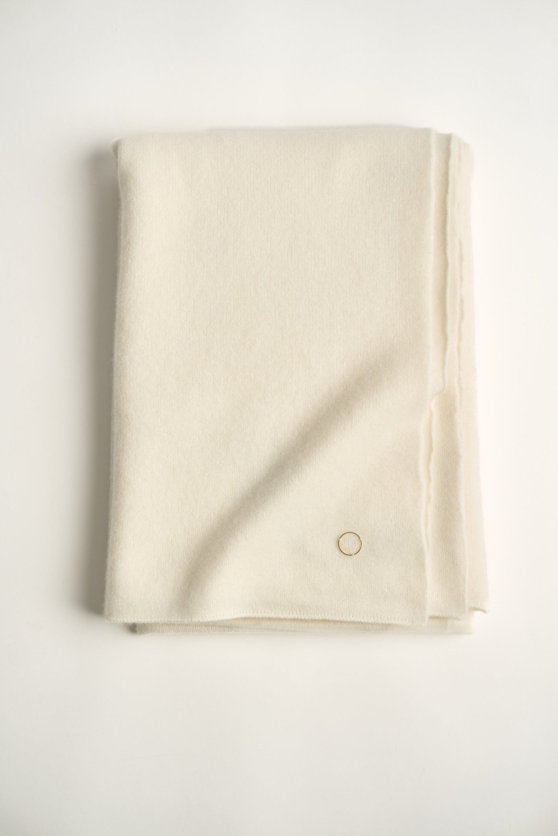 This image displays the "Silence Throw," a luxurious knitted felted throw that offers both warmth and a soft texture. Its unique design, characterized by a subtle, uniform texture and a small, discreet circle detail in the corner, enhances its plush appeal.