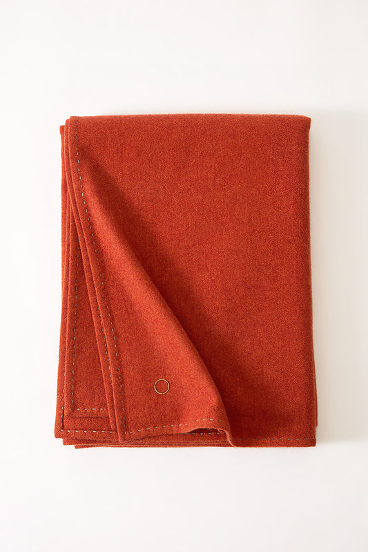 A folded fire Suono throw with hand-stitched edges displayed on a white background.