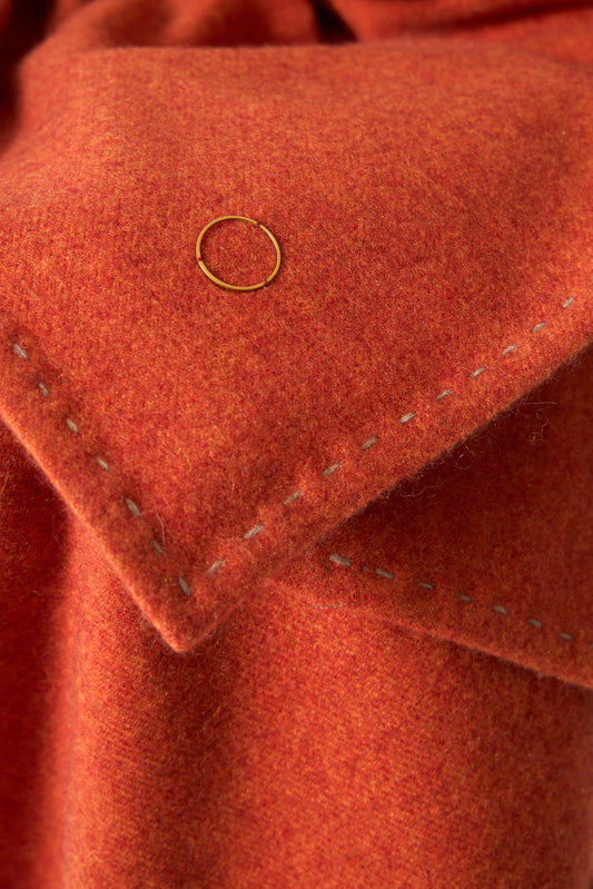 A fire Suono throw with hand-stitched edges, folded over a chair and displayed on a white background.