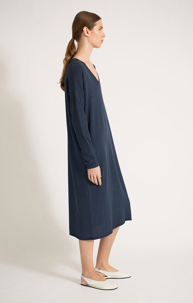 Woman wearing Sylva linear relaxed fit cotton dress with v shaped neckline in colour Indigo. 