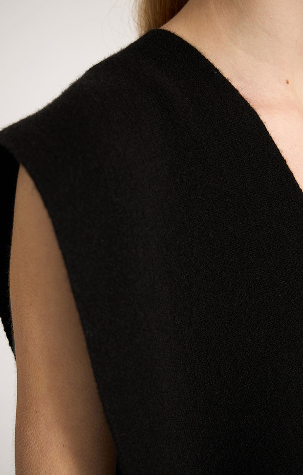 Woman wearing sleeveless cashmere top in colour Black. 